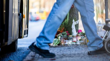 Blumen und Kerzen liegen nach einem Unfall mit einem Doppeldecker-Bus, bei dem eine Jugendliche gestorben ist, an der Bushaltestelle Stadtbad Lankwitz.