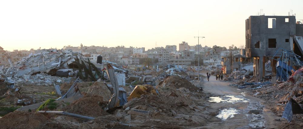 Menschen gehen vorbei an Trümmern und Ruinen auf einer Straße im Flüchtlingslager Al-Maghazi im Zentrum des Gazastreifens. (Bild aufgenommen am 5.03.2024)