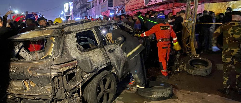 Mitglieder der Zivilverteidigung versammeln sich an einem verbrannten Fahrzeug, das von einem US-Drohnenangriff im Osten Bagdads getroffen wurde. 