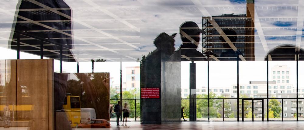 Besucher sind in der Halle der Neuen Nationalgalerie zu sehen, während sich Passanten in der Glasscheibe spiegeln. 