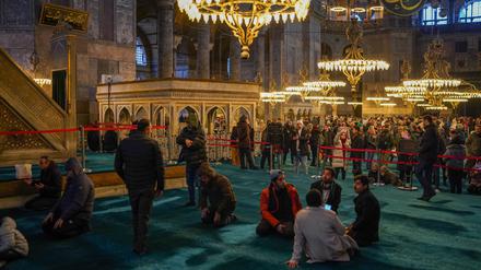 Muslime beten im linken Bereich der Hagia Sophia, während Touristen das Museum auf der rechten Seite besuchen. 