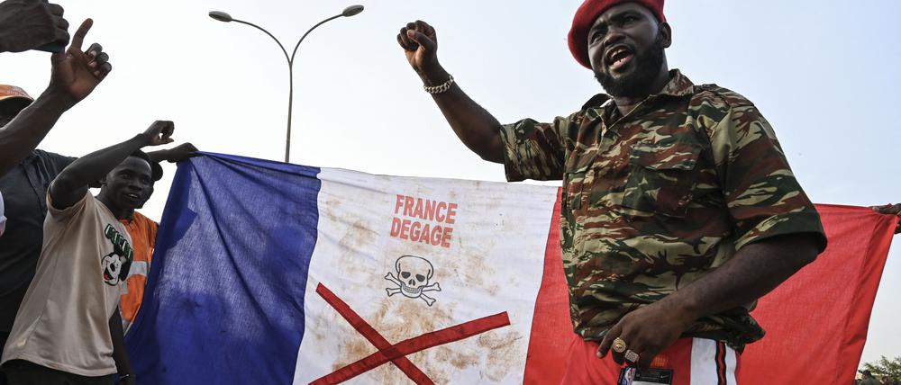 Anhänger des Nigers National Council of Protection of the Homeland (CNSP) zeigen bei einem Protest vor dem französischen Luftwaffenstützpunkt Niamey eine französische Nationalflagge mit einem X-Zeichen.