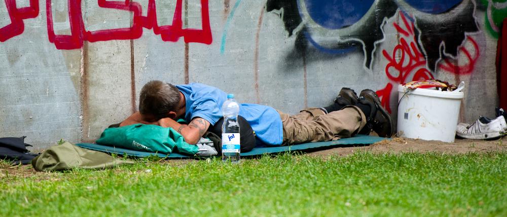 Ein Obdachloser schläft am 21.07.2014 in Berlin am Bahnhof «Zoologischer Garten» neben Bierflaschen.