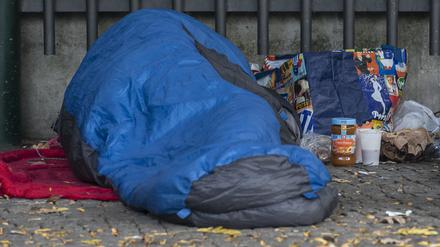 Ein Obdachloser liegt in Berlin in einen Schlafsack gehüllt unter einem Dachvorsprung vor dem Zoo. (Symbolfoto)