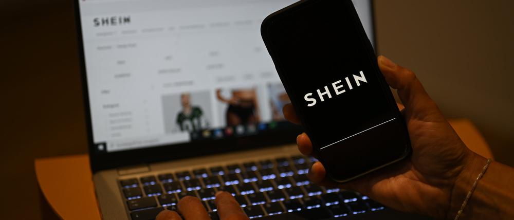 Das Shein-Logo ist auf einem Smartphone zu sehen, während die Webseite des chinesischen Online-Händlers auf einem Laptop geöffnet ist. 
