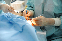 Ein Operateur arbeitet mit chirurgischen Instrumenten an einem Patienten.