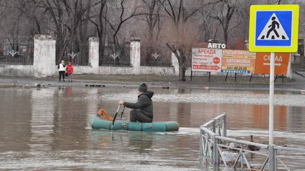 Nachdem ein Damm in der russischen Stadt Orsk gebrochen ist, paddelt ein Mann mit seinem Hund auf einem Schlauchboot durch die überfluteten Straßen.
