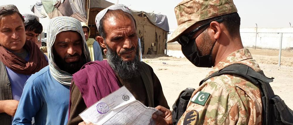 Ein pakistanischer Soldat kontrolliert die Papiere von Afghanen an der Grenze. 