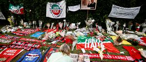 Flaggen der Partei und Memorabilia des AC Mailand, seines früheren Fußballclubs, haben Fans vor der Residenz von Berlusconi bei Mailand abgelegt. 