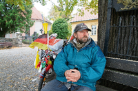 Peter, ein wohnungsloser Zehlendorfer; in seinem "Wohnzimmer" vor der Dorfkirche, der Friedenseiche und der alten Dorfschule in Zehlendorf-Mitte.