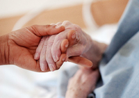 Eine Pflegerin hält einem Altenheim die Hand einer Bewohnerin (Symbolbild).