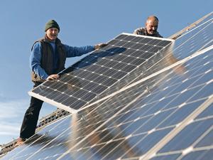 Zwei Arbeiter bei der Montage einer Photovoltaik-Anlage auf einem Hausdach.