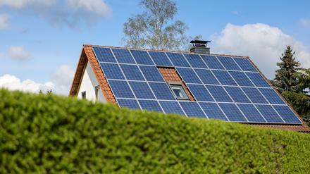Ein Einfamilienhaus mit Solarpaneelen auf dem Hausdach steht hinter einer grünen Hecke. Mehr als die Hälfte aller Einfamilienhäuser in Europa könnten sich laut einer Studie zurzeit selbst vollständig mit Strom und Wärme versorgen.