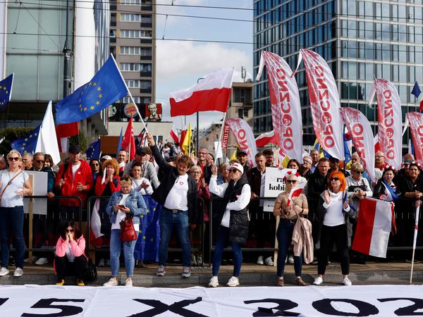 Demonstranci machają flagami Unii Europejskiej i Polski w centrum Warszawy.