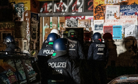 Polizeibeamte stehen bei einer Razzia in der Rigaer Straße in Berlin-Friedrichshain vor einem Haus.