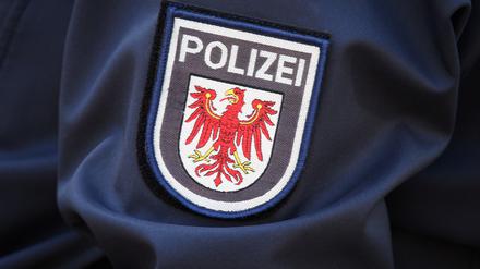 Das Logo der Brandenburger Polizei mit rotem Adler und Schriftzug auf dem Ärmel der Jacke einer Polizeibeamtin.