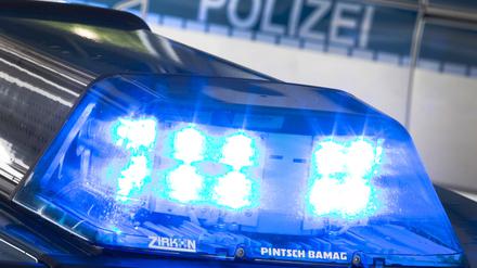 Ein Blaulicht leuchtet auf dem Dach eines Polizeiwagens. Im Hintergrund steht ein weiterer Streifenwagen. (Symbolbild)