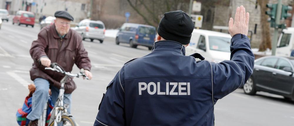 Ein Polizist stoppt einen Fahrradfahrer an der Kaiser-Wilhelm-Straße.