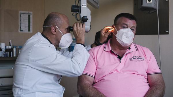 Chefarzt Marc Bloching kontrolliert das Ohr seines Patienten Heiko Dörge