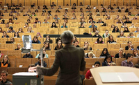 Eine Professorin steht im Hörsaal vor Studierenden.