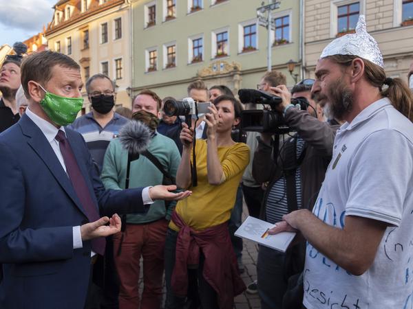 Debattenkultur: Sachsens Ministerpräsident Michael Kretschmer (CDU) spricht in Pirna mit einem Gegner der Corona-Maßnahmen.