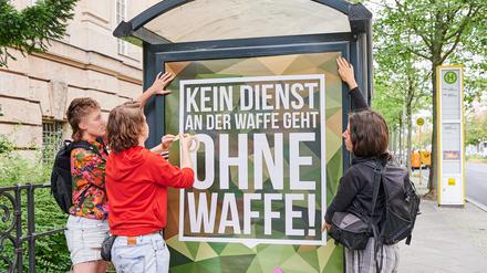 Frida Henkel klebt mit Sympathisantinnen ein Plakat der Bundeswehr mit dem von ihr abgeänderten Slogan „Kein Dienst an der Waffe geht ohne Waffe!“ vor dem Kriminalgericht in Moabit an. 