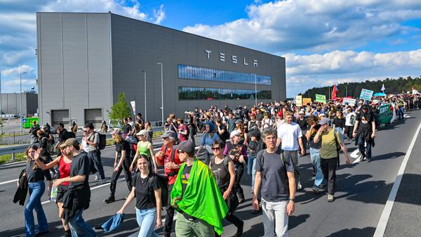 11.05.2024, Brandenburg, Grünheide: Teilnehmer einer Protestveranstaltung gehen zum Werk von Tesla. 