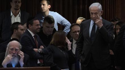 Benjamin Netanjahu (r), Ministerpräsident von Israel, nimmt an einer Abstimmung in der Knesset, dem Parlament des Landes, teil während draußen Menschen gegen den Plan seiner Regierung protestieren.