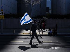 Ein israelischer Demonstrant hält eine Nationalflagge während eines regierungskritischen Protests. 