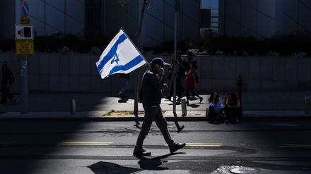 Ein israelischer Demonstrant hält eine Nationalflagge während eines regierungskritischen Protests (Symbolbild)