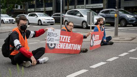 Drei Klimaaktivisten der Gruppe «Aufstand der letzten Generation» blockieren eine Straße in Stuttgart. 