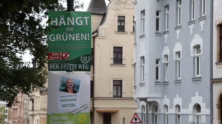 Ein umstrittenes Wahlplakat der Splitterpartei „III Weg“ hängt über einem Plakat der Grünen. 