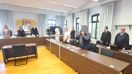 Eine Jugendliche (l) und ein Erwachsener (r) stehen in einem Gerichtssaal des Landgerichtes in Memmingen in der Anklagebank.