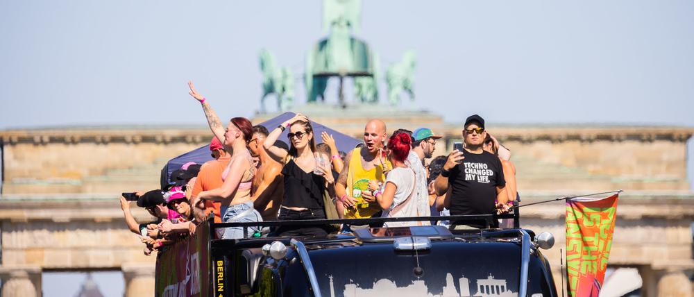 Menschen feiern bei der Technoparade «Rave the Planet» auf einem Wagen vor der Quadriga des Brandenburger Tors.