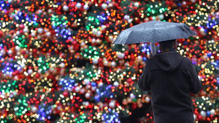 Keine weißen Weihnachten: Ein Mann mit Regenschirm steht auf dem Weihnachtsmarkt am Potsdamer Platz in Berlin (Archivbild).
