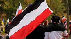 Ein Teilnehmer mit einer schwarz-weiß-roten Reichsflagge während einer Demonstration von Reichsbürgern und anderen Rechtsextremen.