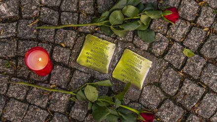 Rosen und eine Kerze liegen neben zwei Stolpersteinen in der Bahnhofstraße in Königs Wusterhausen Dahme-Spreewald. Die Stolpersteine sind ein Projekt des Künstlers Gunter Demnig, das im Jahr 1992 begann. Mit im Boden verlegten kleinen Gedenktafeln, sogenannten Stolpersteinen, soll an das Schicksal der Menschen erinnert werden, die in der Zeit des Nationalsozialismus NS-Zeit verfolgt, ermordet, deportiert, vertrieben oder in den Suizid getrieben wurden Foto: Volker Hohlfeld Stolpersteine *** Roses and a candle lie next to two Stolpersteine in the Bahnhofstraße in Königs Wusterhausen Dahme Spreewald The Stolpersteine are a project by the artist Gunter Demnig, which began in 1992 With small memorial plaques laid in the ground, so-call