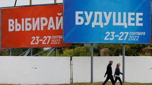 People walk past banners informing about a referendum on the joining of Russian-controlled regions of Ukraine to Russia, in the Russian-controlled city of Melitopol in the Zaporizhzhia region, Ukraine September 26, 2022. Banners read: "Choose. 23-27 September 2022" (L) and "Future. 23-27 September 2022". REUTERS/Alexander Ermochenko