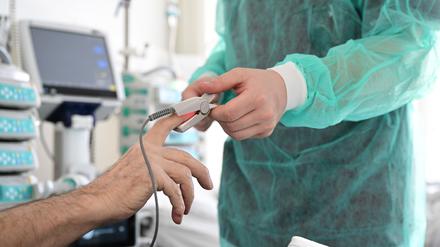 Ein Pfleger legt einem Patienten ein Messgerät an.