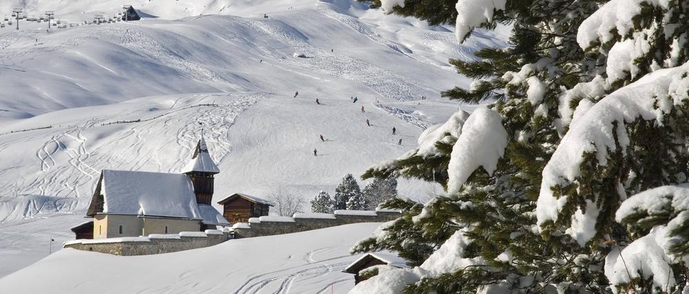 Eine Kirche steht in einer verschneiten Berglandschaft.