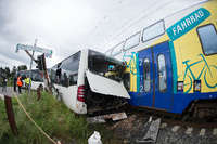 Ein Zug steht nach einem Zusammenstoß mit einem Schulbus auf den Gleisen. Bei dem Unfall wurde ein Mensch leicht verletzt.