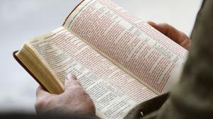 Eine Person hält eine Bibel in der Hand, während die Bibel im Kapitol von Utah vorgelesen wird. 