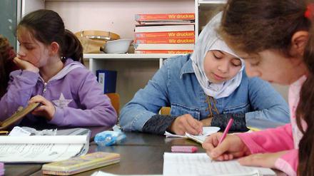 Schüler und Schülerinnen einer Grundschule in Berlin-Kreuzberg lernen mit ihrer Lehrerin im Unterricht.