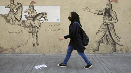 Ein Mädchen geht an einer Häuserfassade im Iran entlang. 