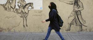 Ein Mädchen geht an einer Häuserfassade im Iran entlang. 