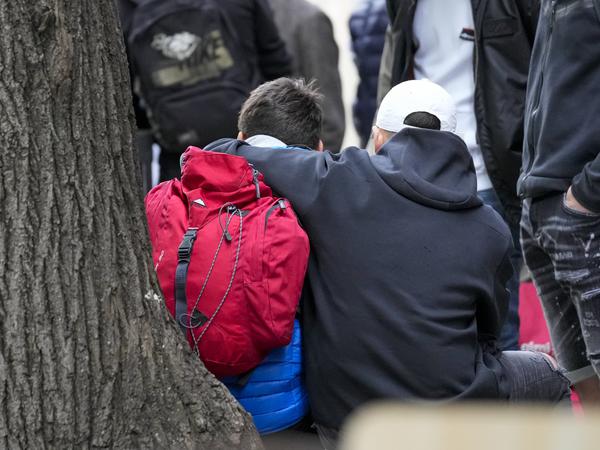 Zwei Kinder nehmen sich in einem abgesperrten Bereich an einer Grundschule in den Arm. 