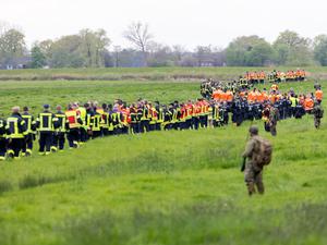 Soldaten der Bundeswehr und Einsatzkräfte von Feuerwehr und Polizei stellen sich auf, um ein Feld abzusuchen.  