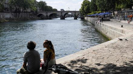 Ein Paar sitzt an dem Ufer der Seine. 