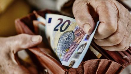 Eine Seniorin zieht einen 20 Euro Schein aus ihrem Portemonnaie. 