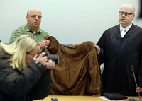 Eine 32 Jahre alte Frau wird am Dienstag in Siegen (Nordrhein-Westfalen) von ihrem Anwalt Daniel Nierenz (r) und einem Anwaltsgehilfen (hinten links) mit einer Jacke verdeckt. Die Frau muss sich vor dem Landgericht wegen des Todes ihrer beiden Kinder verantworten.